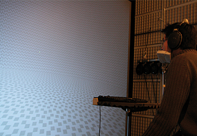 Illustration of the setup used during the experiment. The participant wore headphones and sat in front of the large screen with head fixed by a chin-rest. A mouse fixed on a small tablet allowed to monitor the virtual pointer to report the perceived auditory localization.