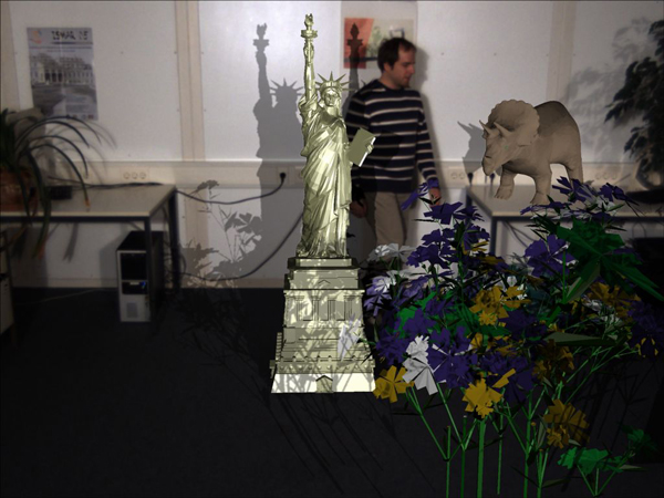 Closeup on a final composited image. Note the mutual shadowing between virtual content and background and between virtual object and dynamic real content. (e.g. the shadows of the Statue of Liberty on the person.)