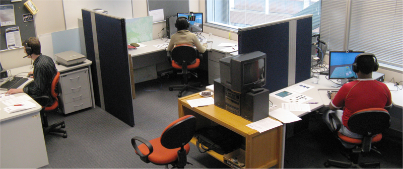 Photo of the experimental setup with three participants. The participants are isolated visually by office walls and acoustically by headsets that completely cover the ears.